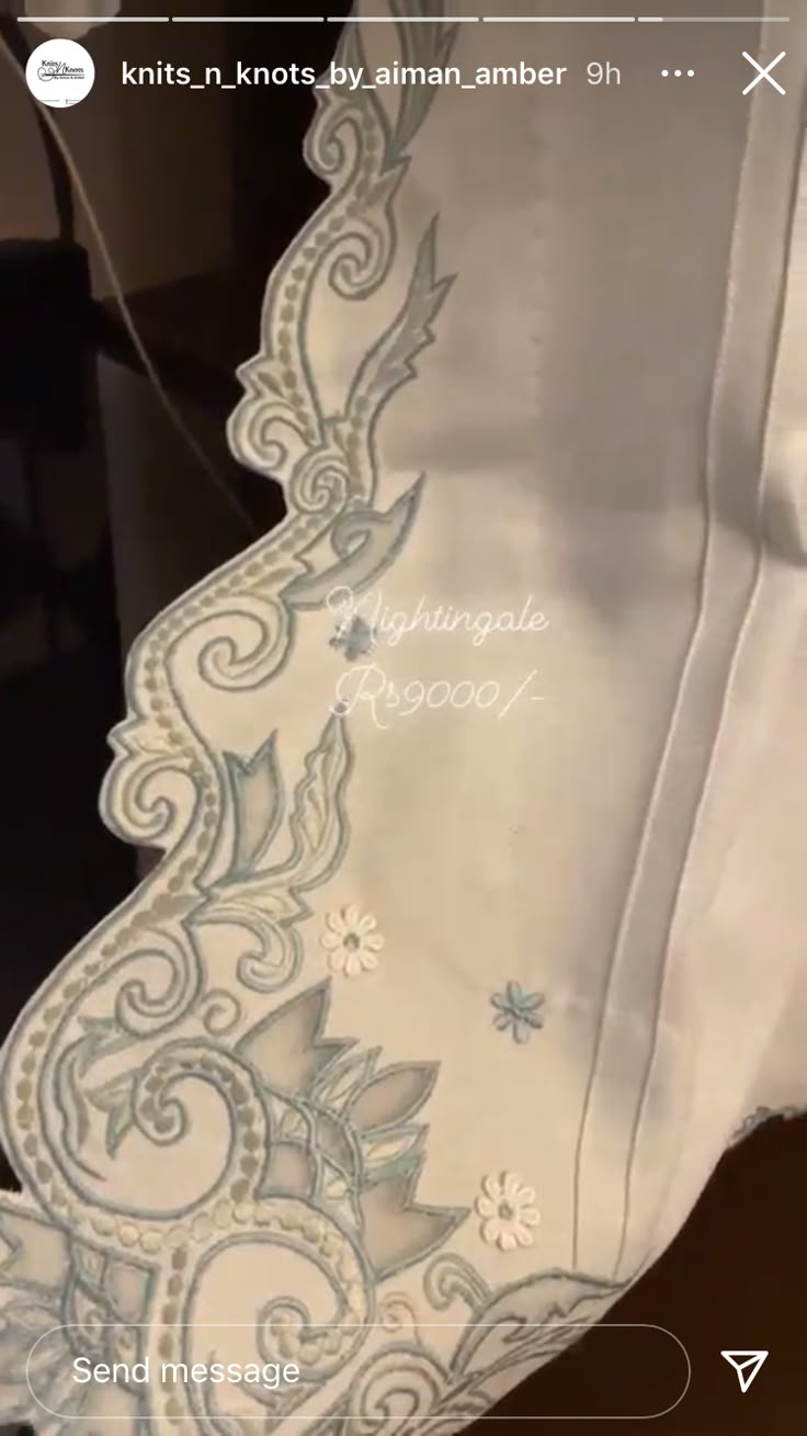 the back of a white dress with an embroidered design