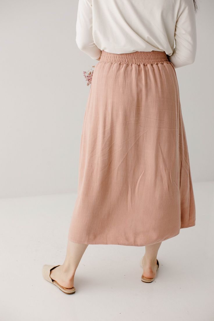 Start your day in style with the 'Greta' Skirt! This midi length, linen-blend skirt is light and airy for spring and summer and features button-down detailing for a fun touch. Pair the 'Greta' with all your favorite tops for Sunday morning or a day at the farmer's market! 30% Linen 70% Rayon Hand Wash Cold Hang to Dry Low Iron if Needed Do Not Dry Clean Fully Lined Model in Blush Height 5'2" | Wearing Size Small Model in Black Height 5'9" | Wearing Size Small Please carefully measure a similar i Spring Daywear Maxi Skirt With Gathered Design, Spring Maxi Skirt With Elastic Waistband For Daywear, Spring Relaxed Long Maxi Skirt, Relaxed Rayon Summer Skirt, Summer Rayon Relaxed Skirt, Summer Rayon Skirt With Relaxed Fit, Linen Flowy Skirt For Vacation, Relaxed Midi Skirt For Spring, Rayon Midi Skirt For Vacation