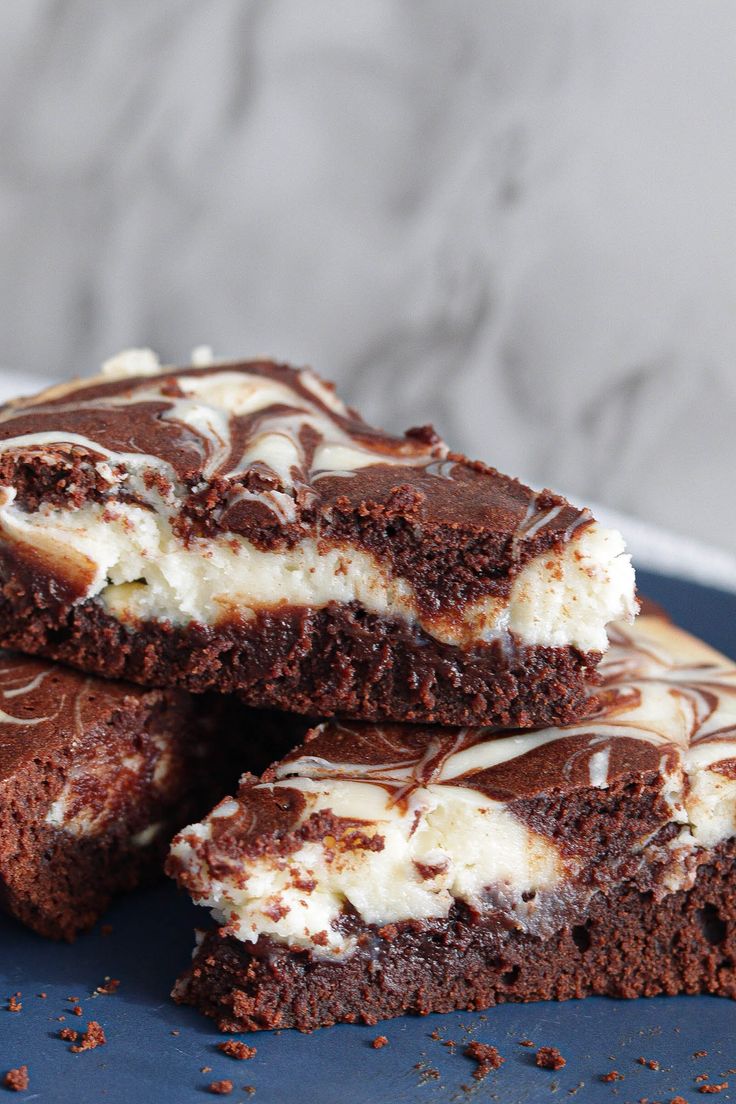 three pieces of chocolate cake on a blue plate with white frosting and drizzled