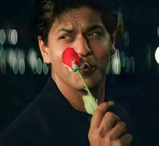 a man holding a rose in front of his face with a clown nose on it