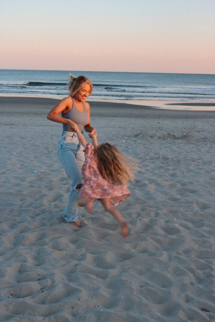 two girls playing in the sand at the beach