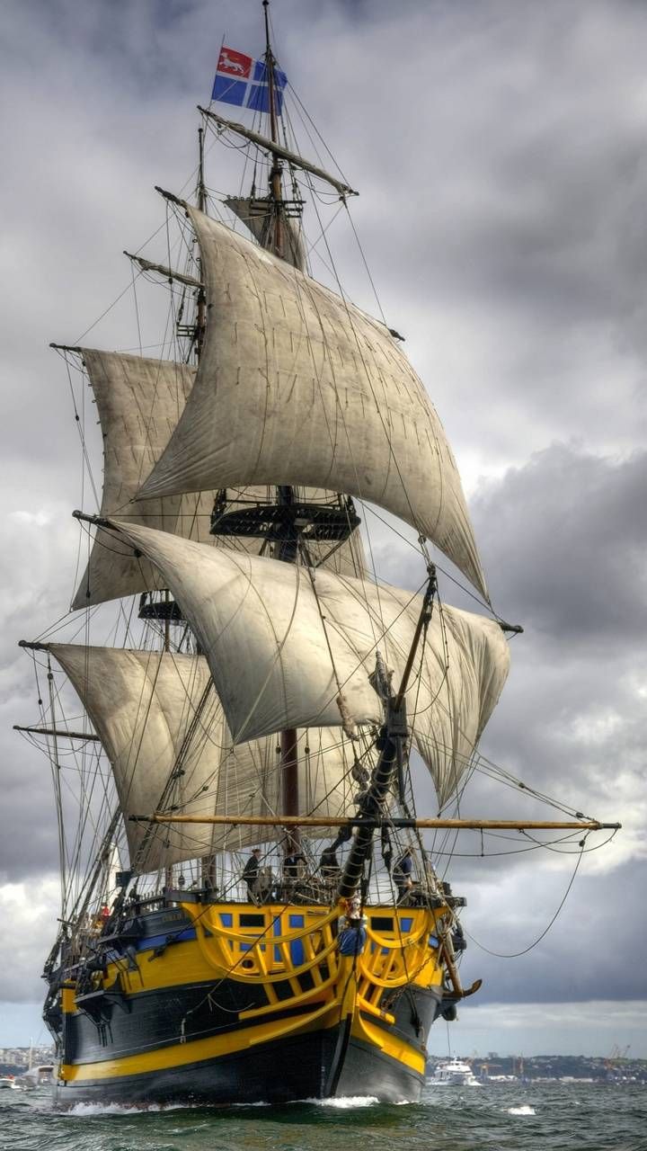 a large white and yellow boat in the ocean on a cloudy day with grey skies