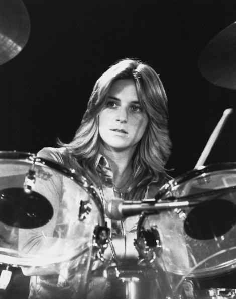 a woman sitting behind a drum set