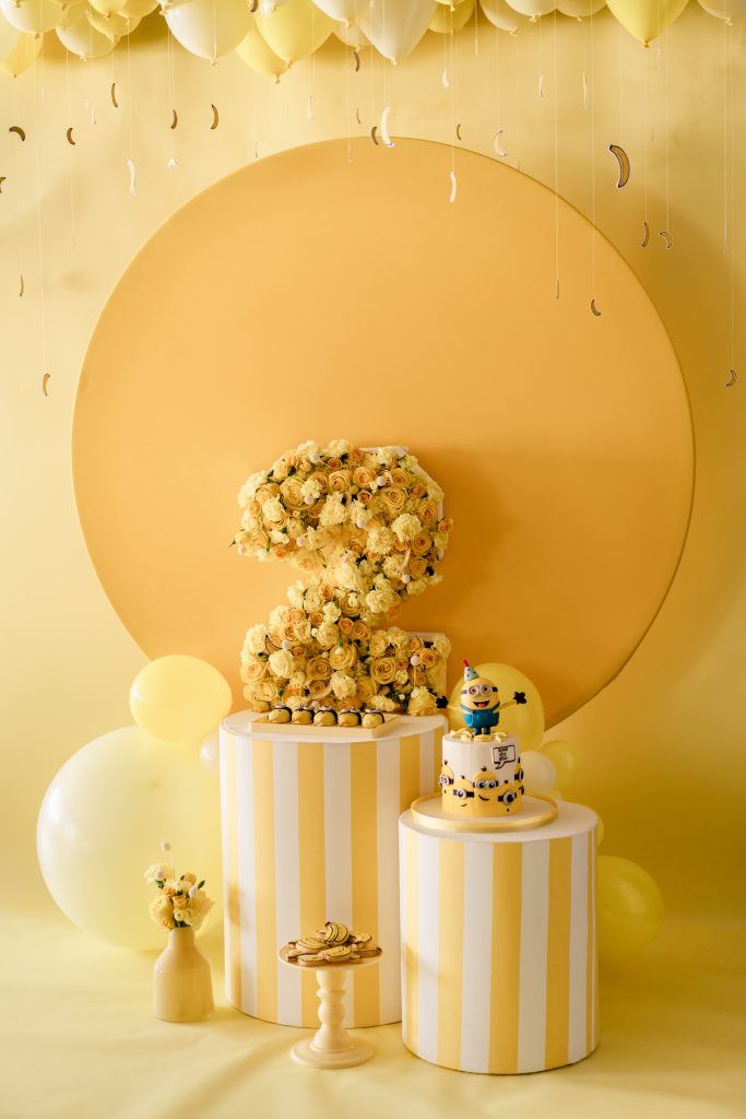 a yellow and white cake surrounded by balloons