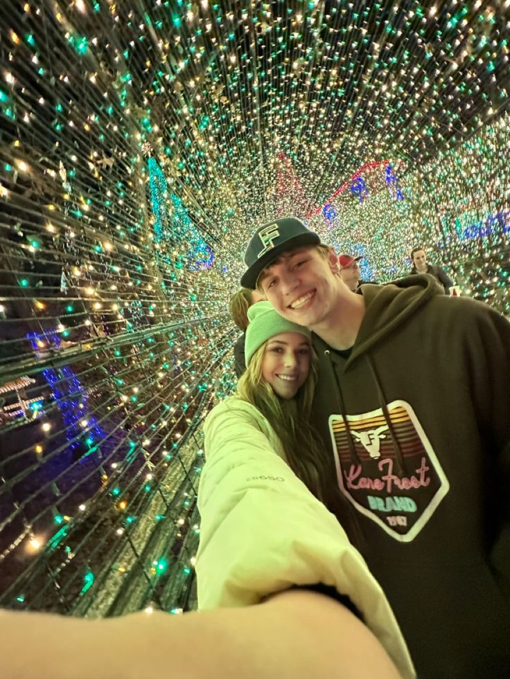 a man and woman taking a selfie in front of a large display of lights