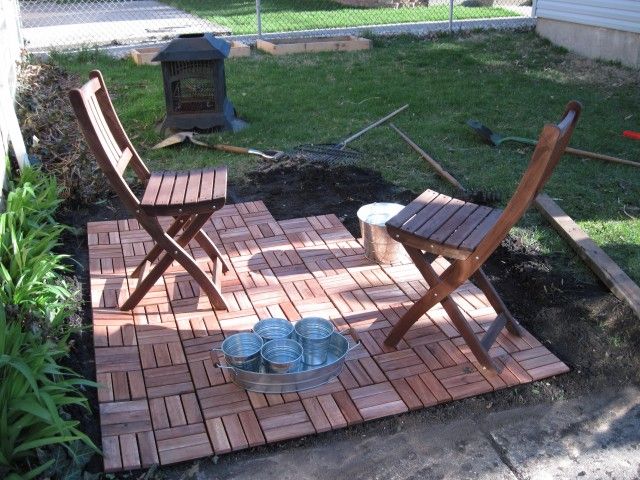 two wooden chairs sitting on top of a brick patio next to a fire hydrant