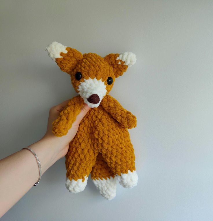 a hand holding a stuffed animal that looks like a fox