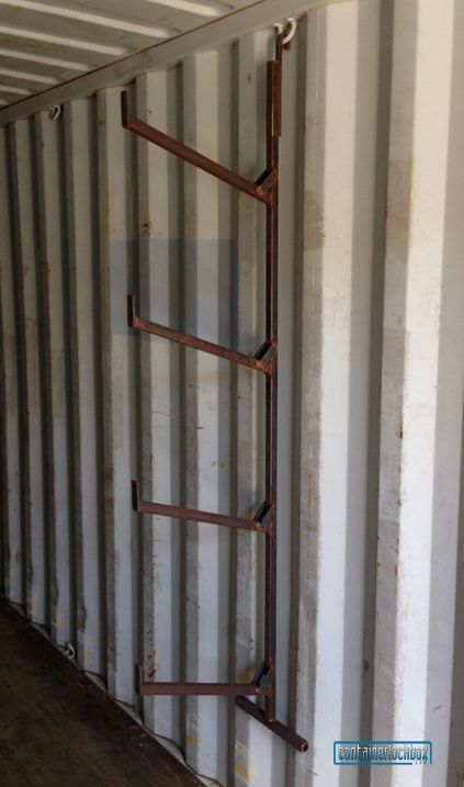 an old ladder leaning against the wall in a storage room with metal bars attached to it