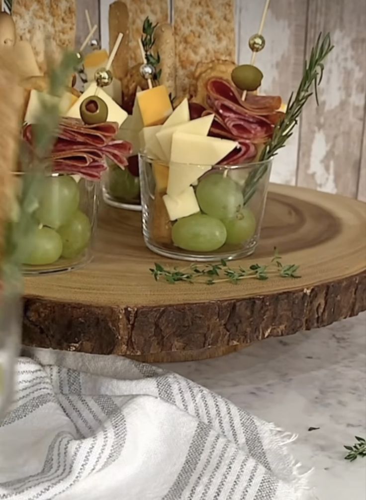 an appetizer platter with grapes, cheese and crackers on a wooden tray