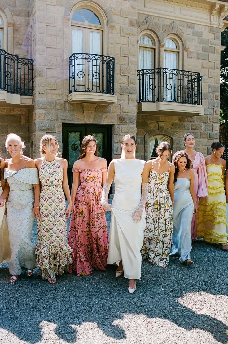 a group of women standing next to each other in front of a large stone building