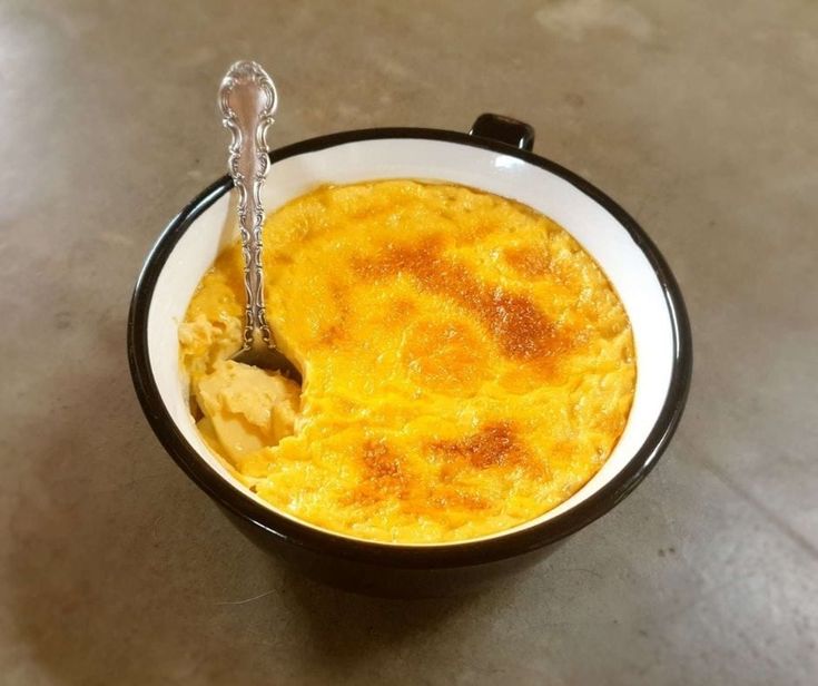 an omelet in a black and white bowl with a spoon