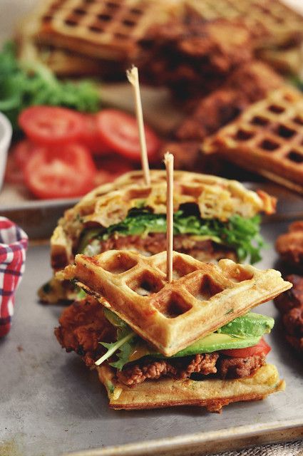 a waffle sandwich with meat, lettuce and tomato slices on the side