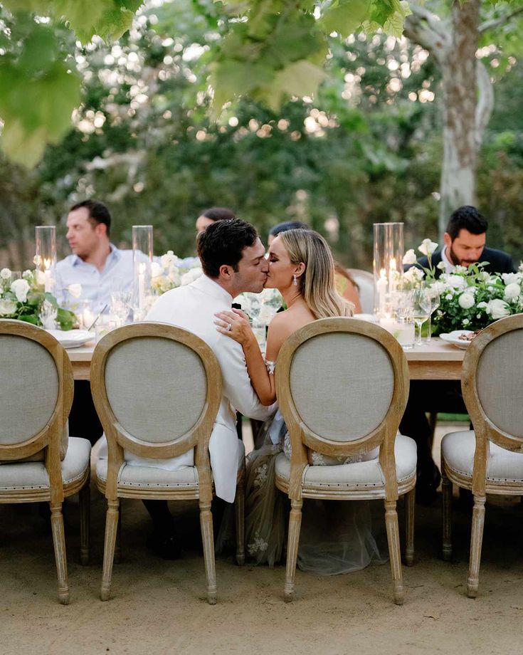 a bride and groom kissing at the dinner table