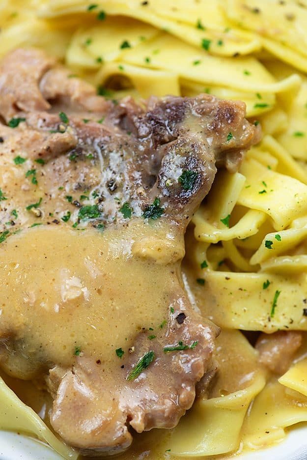 a white plate topped with pasta and meat covered in gravy