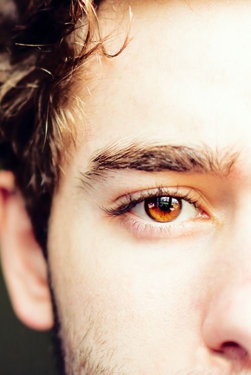 a close up of a man's face with an orange colored eye and beard