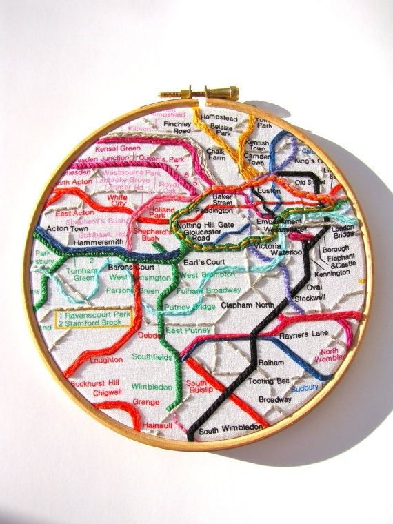 a cross stitch map is hanging on a wall in the shape of a round frame