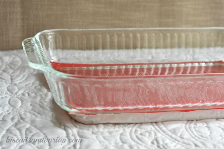 a glass baking dish with red liquid in it on a white tableclothed surface