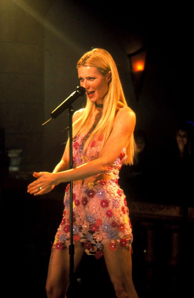 a woman standing in front of a microphone on stage with her hand out to the side