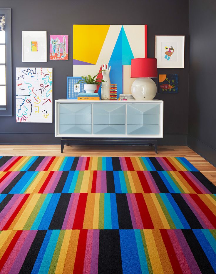 a brightly colored area rug in the middle of a room with artwork on the wall