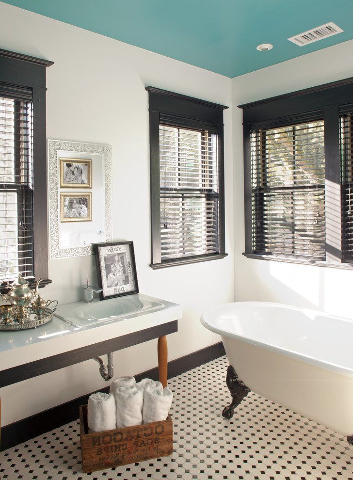 a bathroom with black and white checkered flooring, two windows above the bathtub