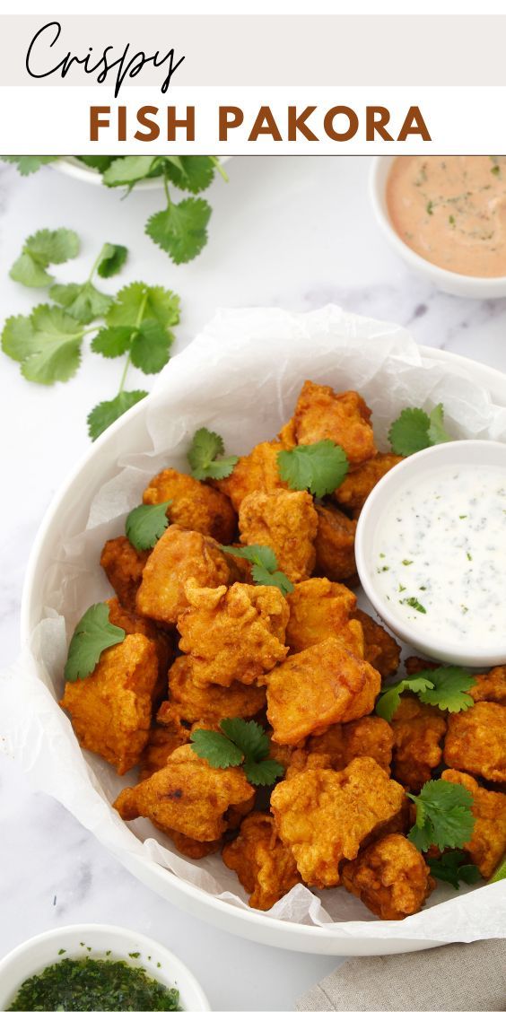 crispy fish pakora in a bowl with dipping sauce and cilantro on the side