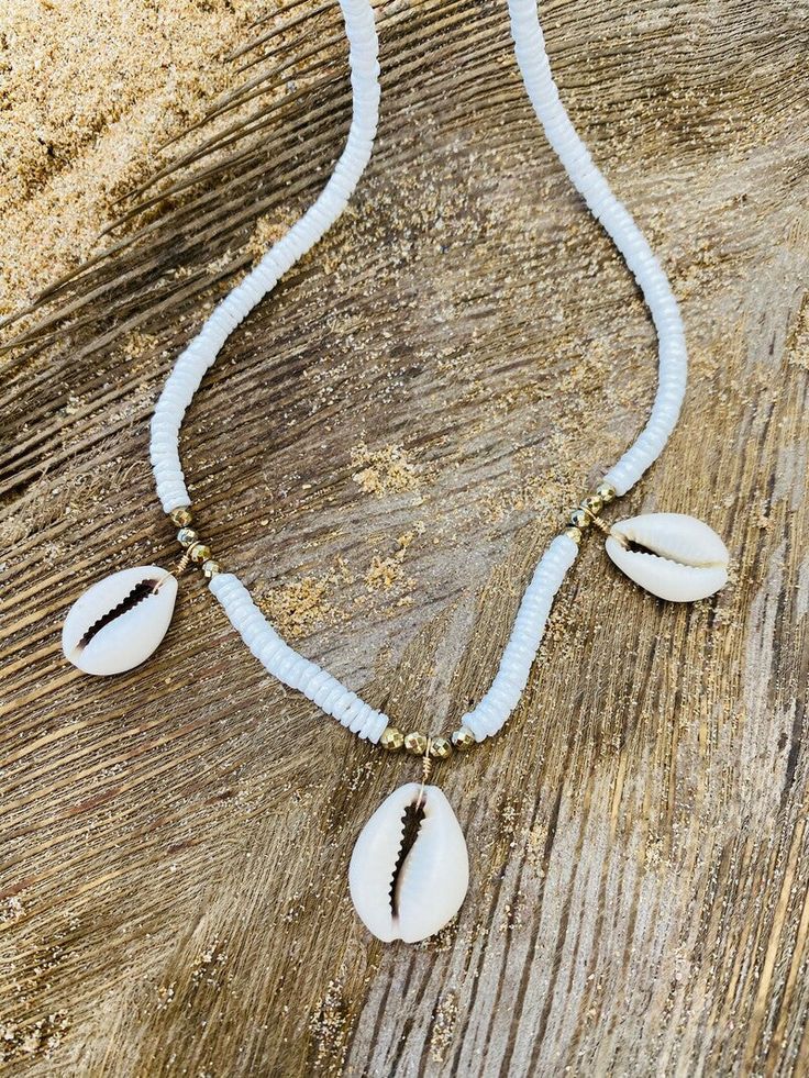 All About Cowrie Shells Necklace. Inspired by the beautiful Cowry Shells of Puerto Rico and Virgin Island beaches, this stunning necklace incorporates natural Cowrie Shells, White Claw Shell and Golden Hematite for a touch of Sparkle. Clasps and Wires 14Kt God filled. Length 18” Made with love in Miami. According to the African legends, the cowrie shells are representing the goddess protection which is highly powerful and is connected with the strength and power of the Ocean. Due to this, the cowrie shells are also been recognized as prosperity. Even more, these shells also symbolize the power of destiny. Shells Necklace, Virgin Island, White Claw, Cowrie Shell Necklace, Cowry Shell, Cowrie Shells, Jewelry Lookbook, Cowrie Shell, Evil Eye Jewelry