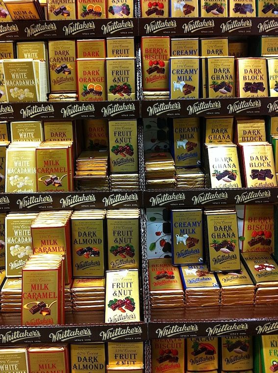 many books are stacked on top of each other in a book store display case that is filled with gold and chocolates