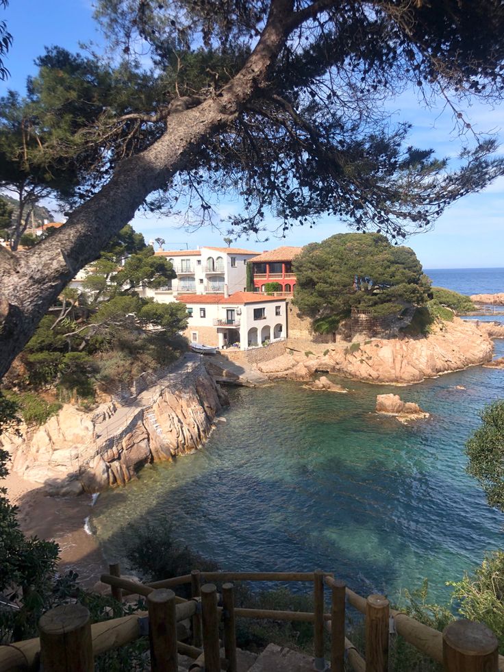 the house is on top of a cliff overlooking the ocean and trees in front of it