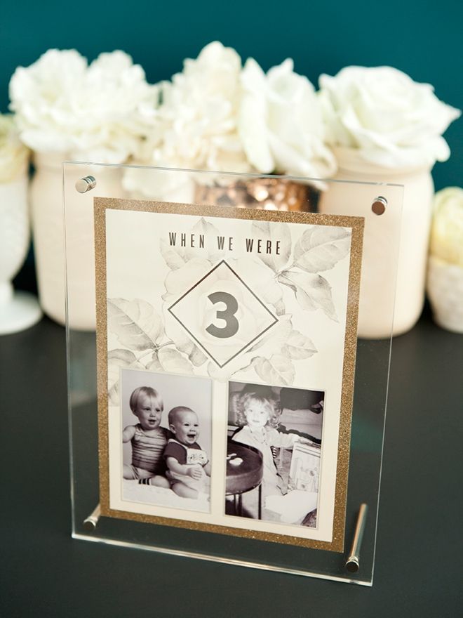 a clear acrylic frame with two photos on it and flowers in the background