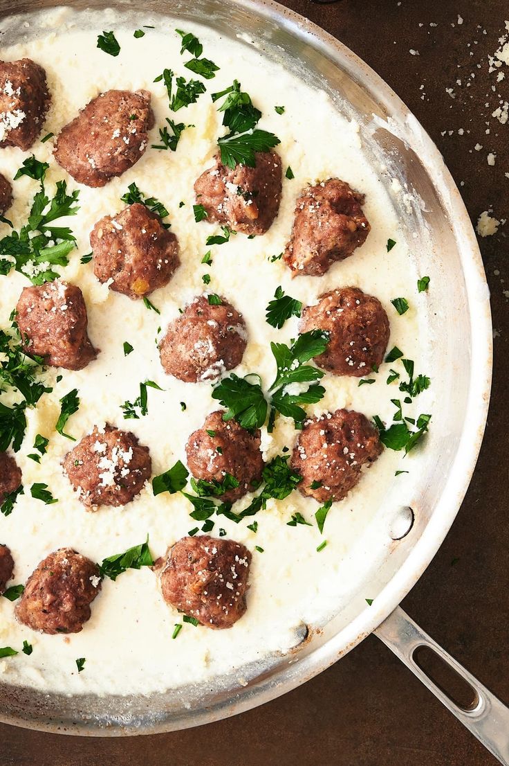 a pan filled with meatballs covered in sauce and parsley