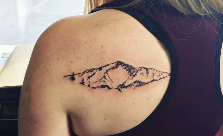 a woman with a mountain tattoo on her shoulder