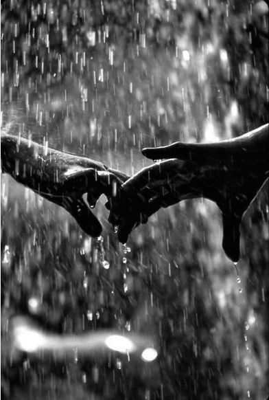 two hands holding each other in the rain