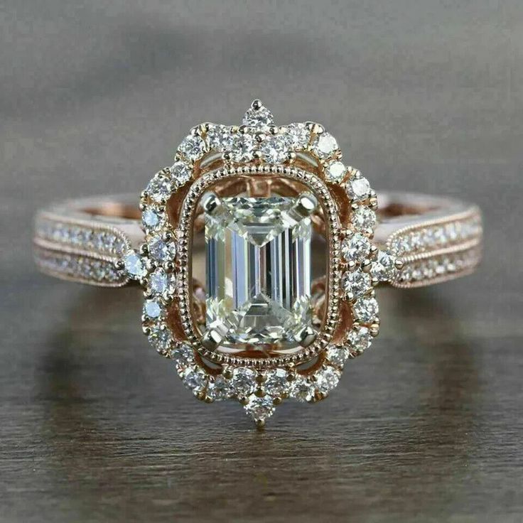 a fancy engagement ring with an emerald center surrounded by diamonds