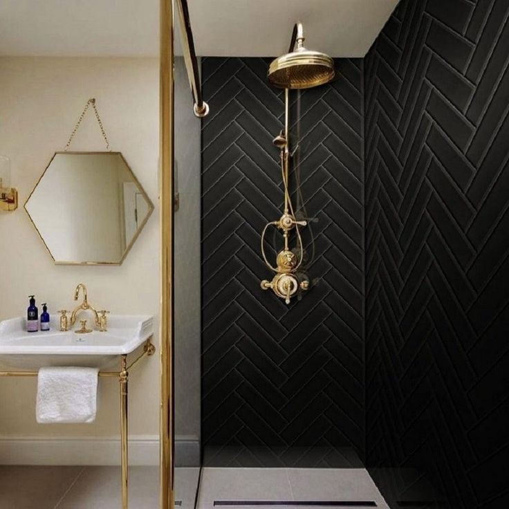 a black and white bathroom with gold fixtures on the shower head, sink and mirror