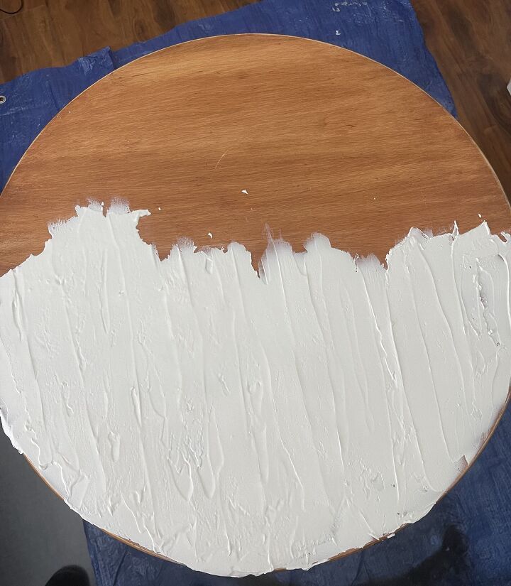 a round wooden table with white paint on it