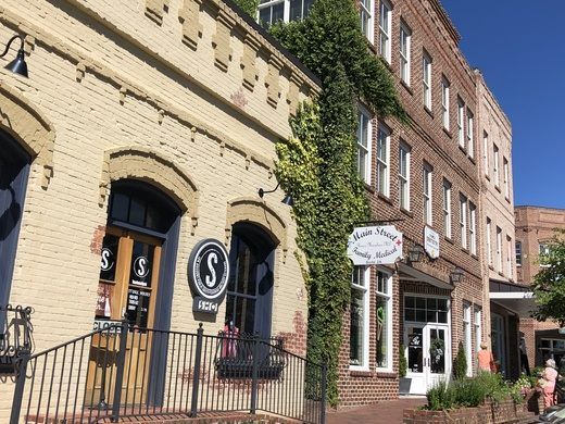 an old brick building with ivy growing on it's side and people walking down the street