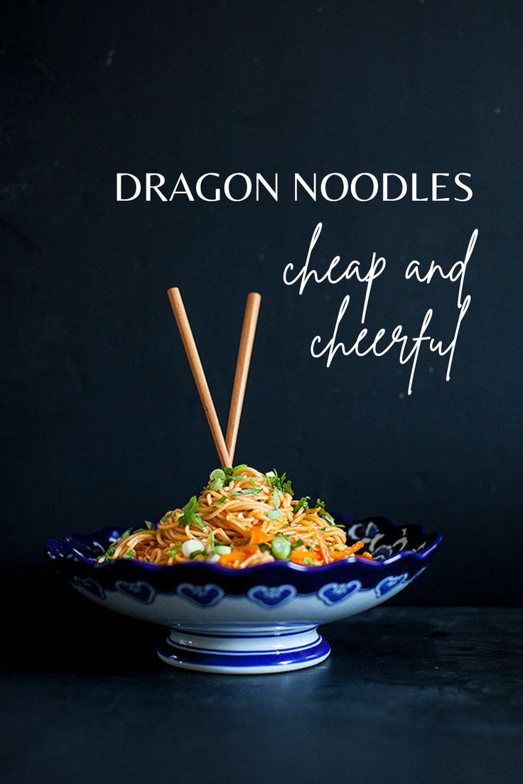 a bowl filled with noodles and chopsticks on top of a black countertop