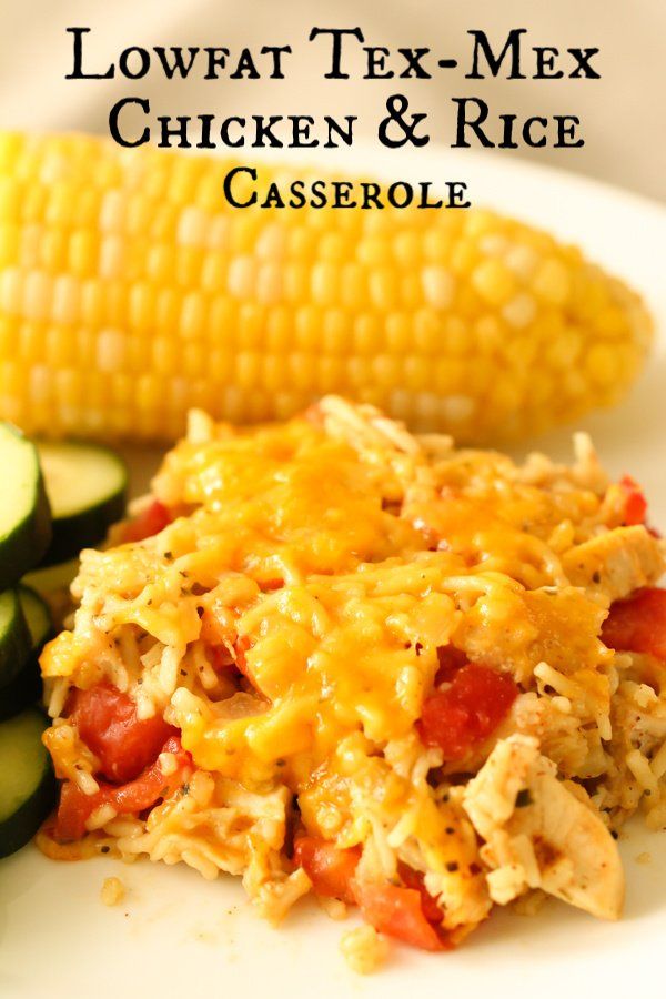 a white plate topped with chicken and rice casserole next to a cob of cucumbers