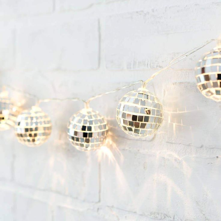 disco ball lights are hanging on a white brick wall