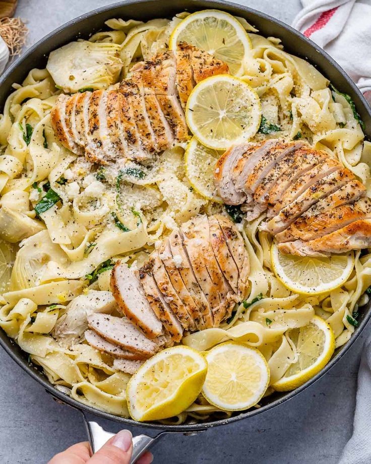 a skillet filled with chicken, pasta and lemons