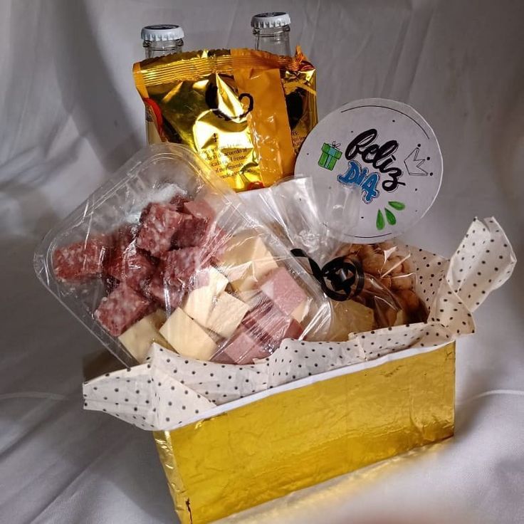 a box filled with assorted snacks on top of a white cloth covered tablecloth