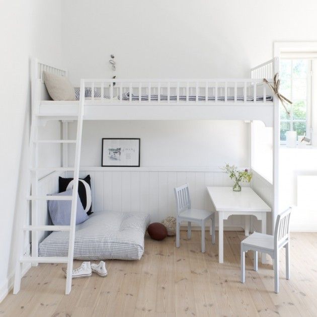 a white bunk bed sitting next to a table and chair in a room with wooden floors