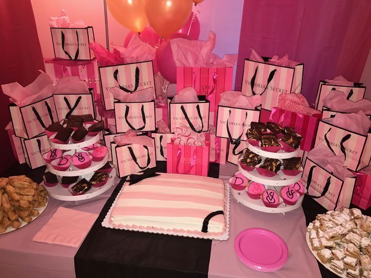 a table topped with lots of cakes and desserts covered in pink ribboned bags