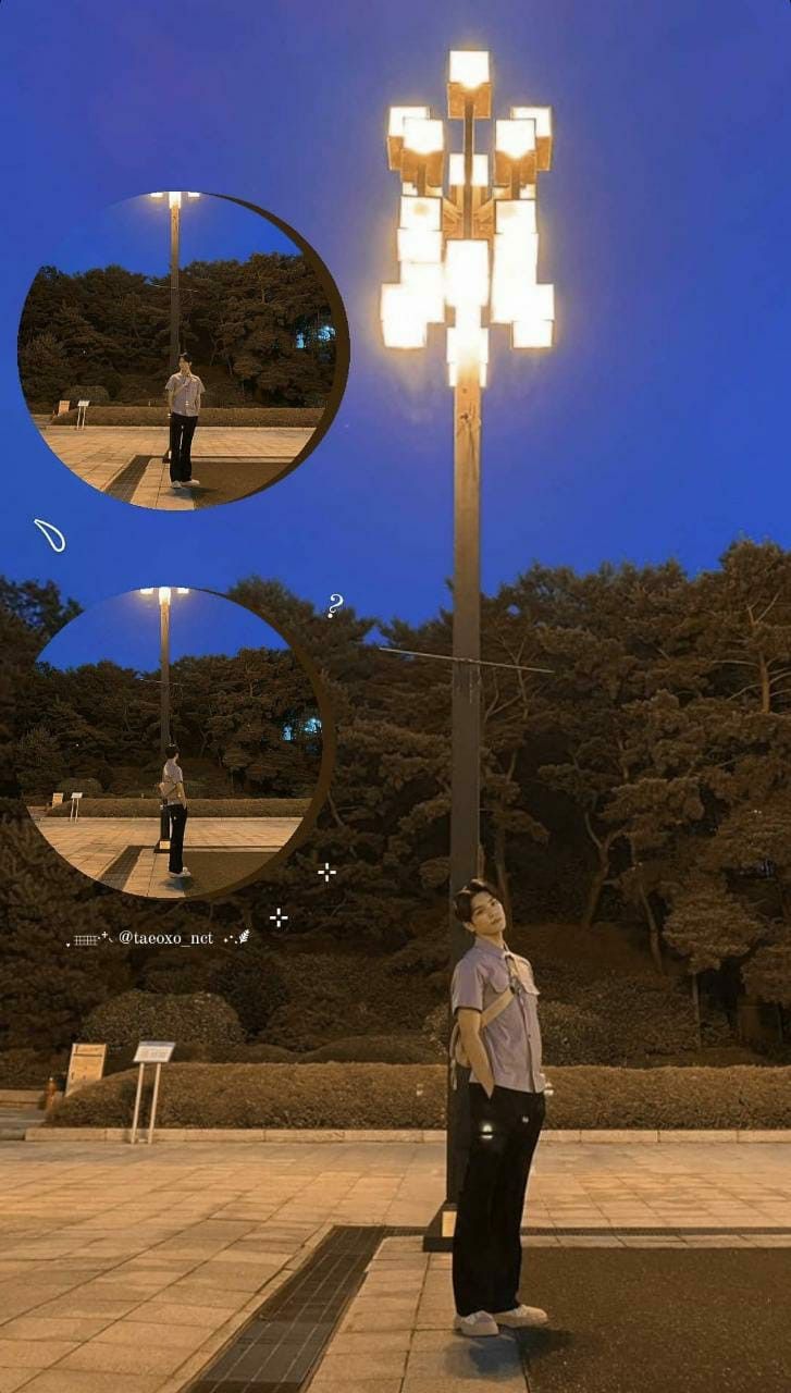 a woman standing under a street light next to a park with trees in the background