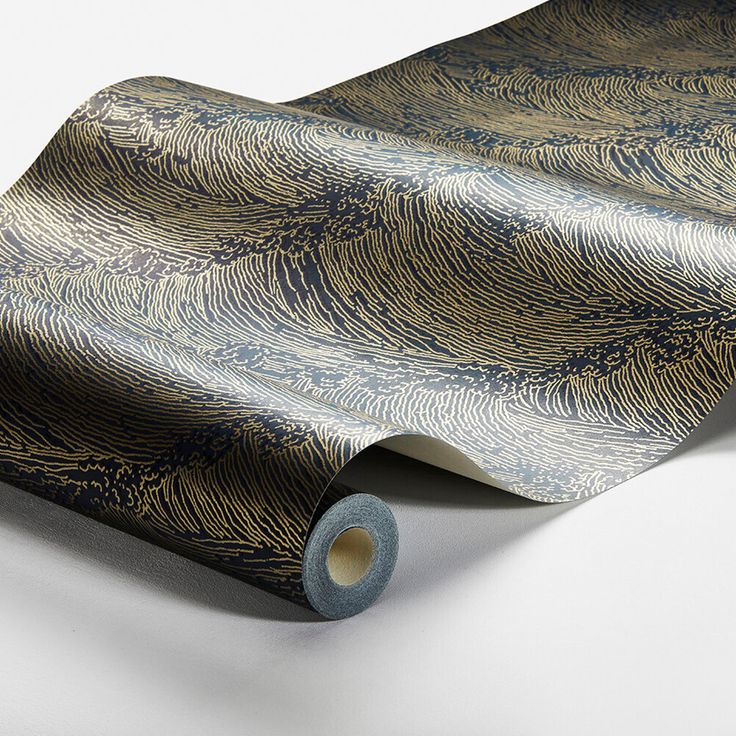 a roll of blue and gold wallpaper on a white surface