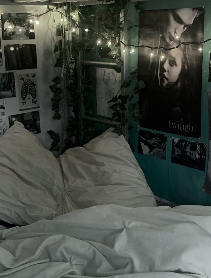 an unmade bed with white sheets and fairy lights strung from the wall above it