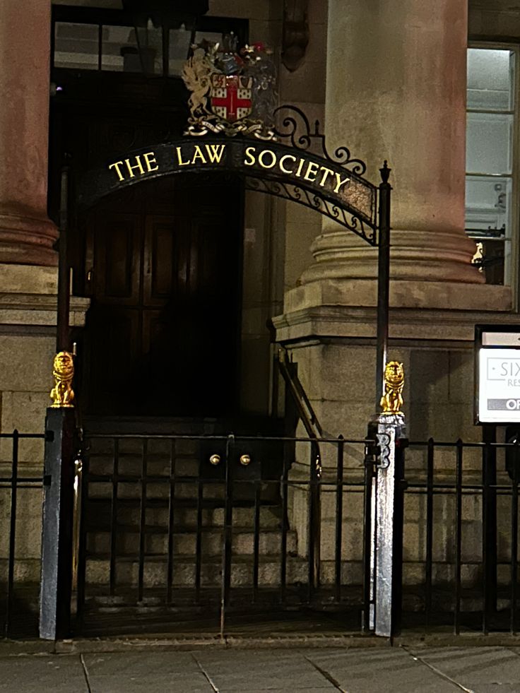 an entrance to the law society in london at night with street signs on it's sides