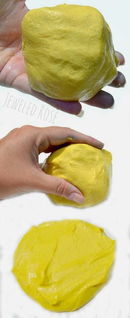 two hands holding yellow powdered dough on top of a white surface with another hand reaching for it