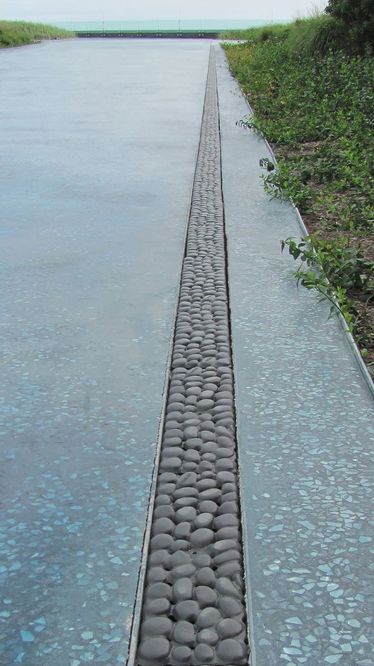 a long line of stones sitting on the side of a road next to a body of water