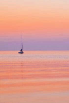 a sailboat floating in the ocean at sunset or dawn with pink and purple hues